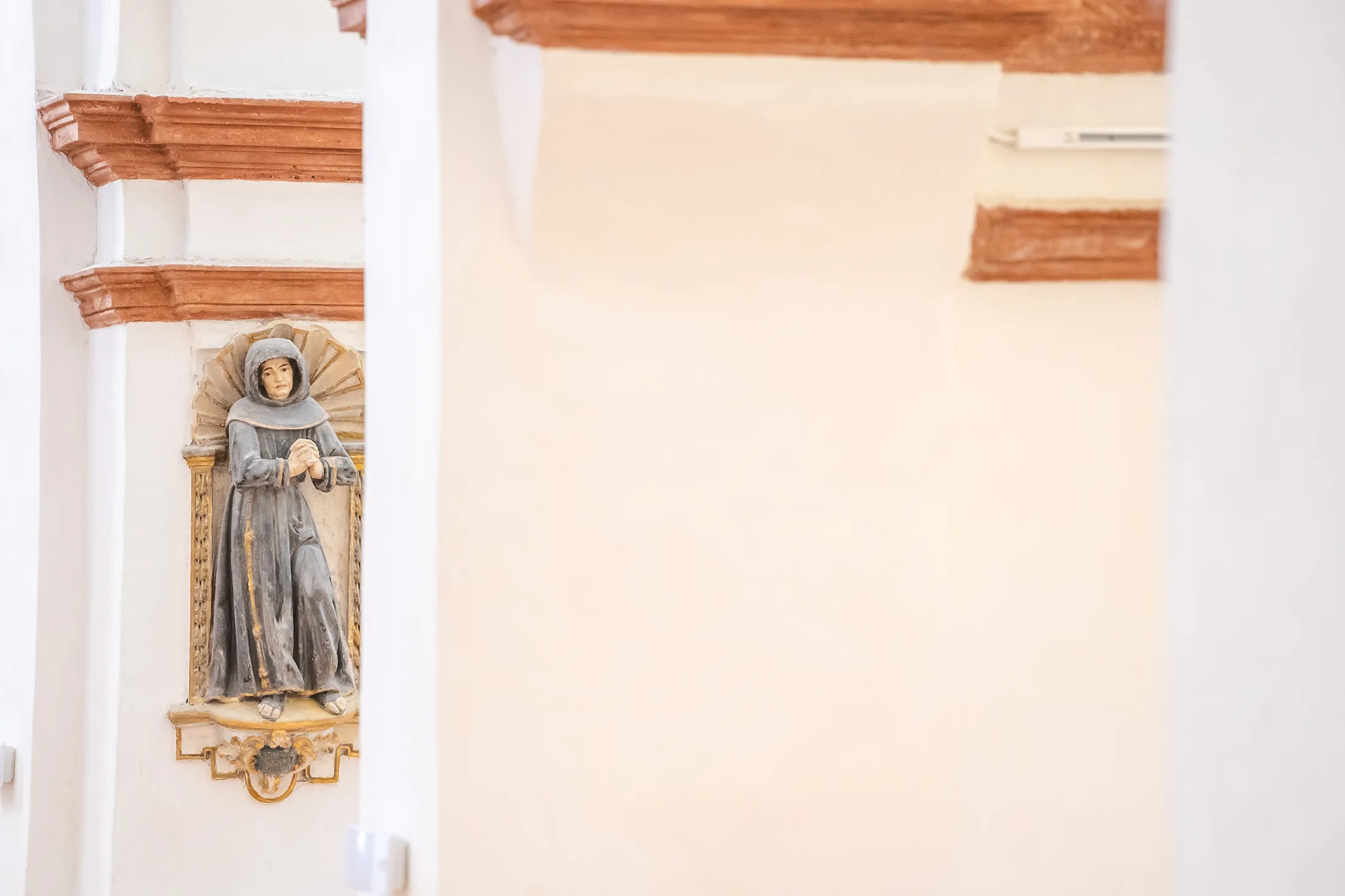 Hornacina restaurada en un pilar conservando una pequeña estatua religiosa